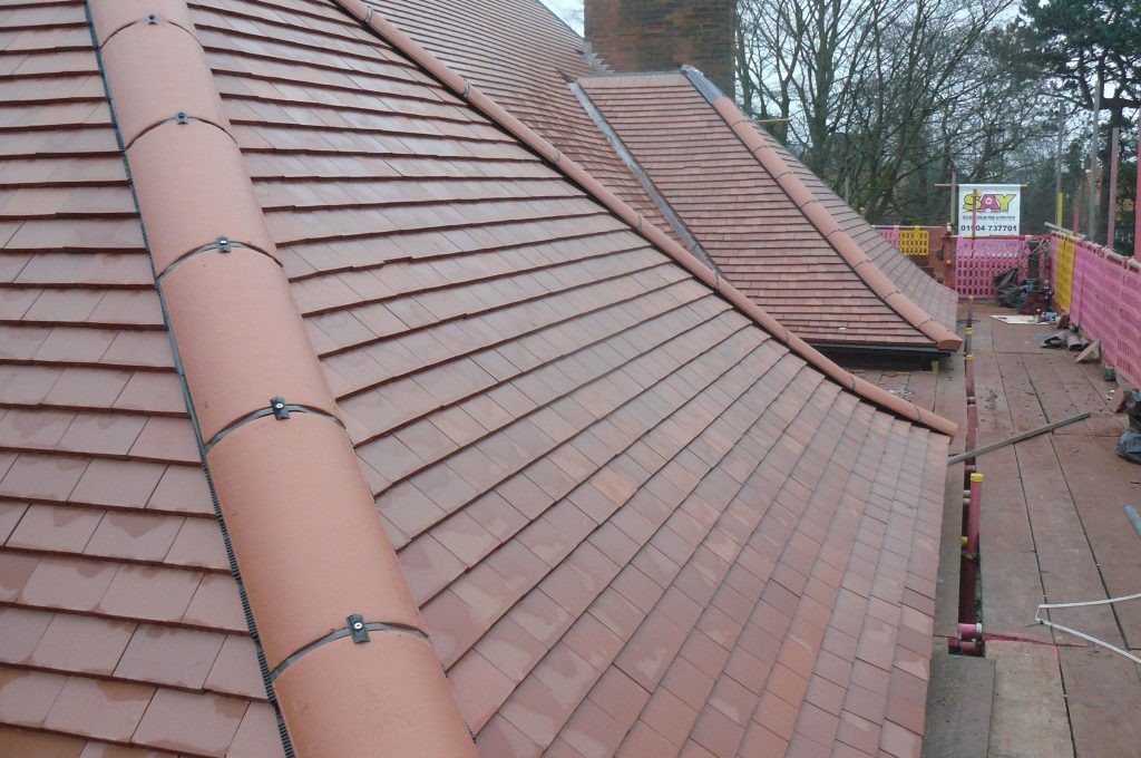 Red-brown tiled roof with hip tiles and visible fixings
