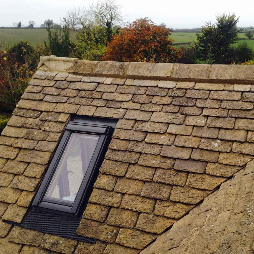 Black-framed rooflight set into stone roof courses