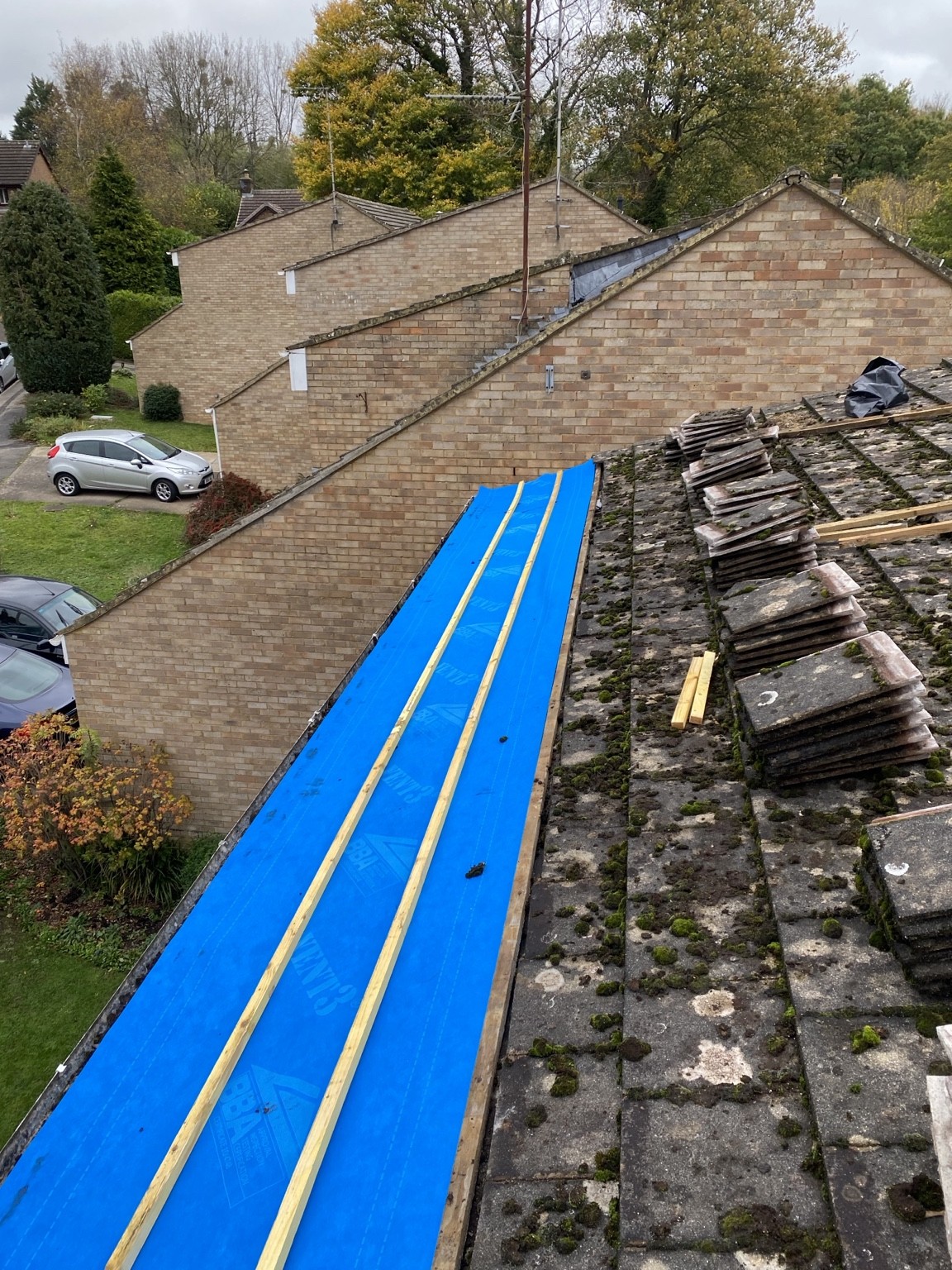 Blue roof underlay and battens beside stacked stone roof coverings