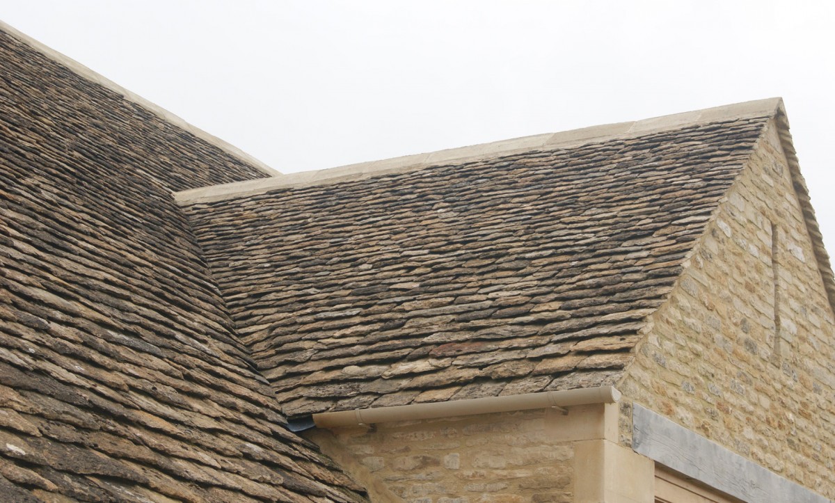 Stone roof slopes meeting at a valley above a stone wall